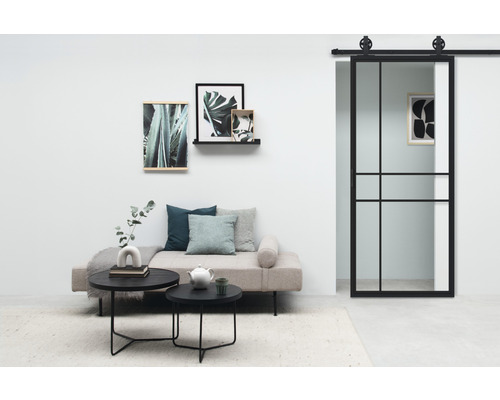 Wohnzimmer mit Sofa, Couchtischen, Wandbildern und Schiebetür