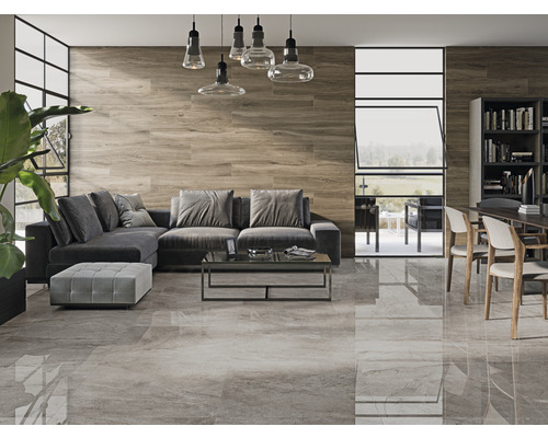 Wohnzimmer mit grauen Bodenfliesen, Holzwand, grauer Couch und Esstisch mit Stühlen