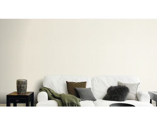 Wohnzimmer mit weißer Couch, Kissen und Beistelltisch vor einer Wand