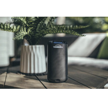 Thermocell Mückenschutzgerät auf einem Holztisch mit Pflanze im Hintergrund