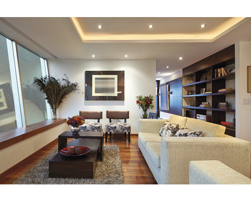 Wohnzimmer mit Sofa, Sesseln, Couchtischen und Regalen