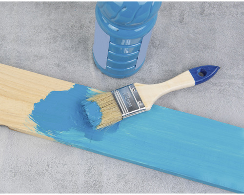 Holzbrett wird mit Farbe und einem Pinsel gestrichen