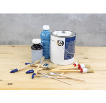 Farbeimer, Lackflasche und Pinsel auf einem Holztisch