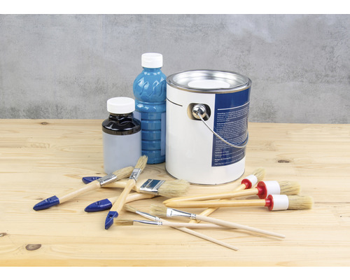 Farbeimer, Lackflasche und Pinsel auf einem Holztisch