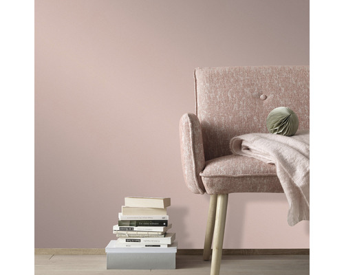 Wohnzimmer mit Sessel, Büchern und Dekoration vor einer Wand