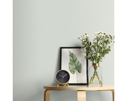 Wohnszene mit Tisch, Uhr, Blumen und gerahmtem Bild an einer Wand