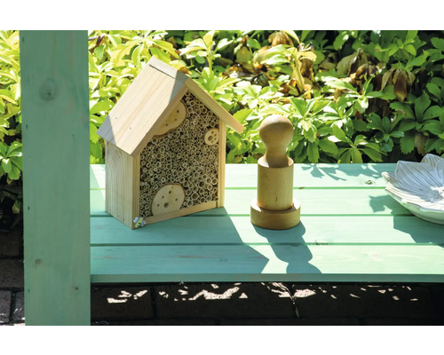 Insektenhotel aus Holz mit Füllmaterial aus Röhrchen und hölzernen Dekorationen.