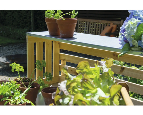 Gartenszene mit Kräutern, Salat und einem Gartentisch aus Holz.