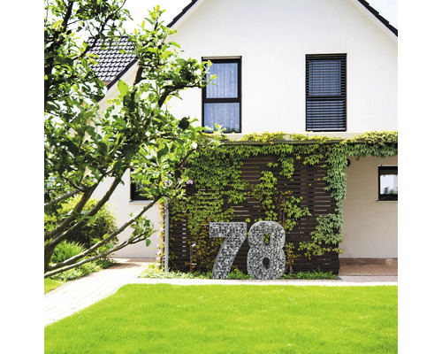 Hausfassade mit Hausnummer aus Gabionen vor Grünfläche