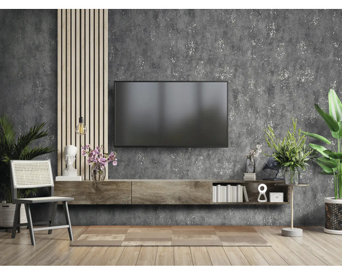 Wohnzimmer mit Fernseher, Lowboard, Stuhl und Dekorationen vor einer Wand mit Struktur