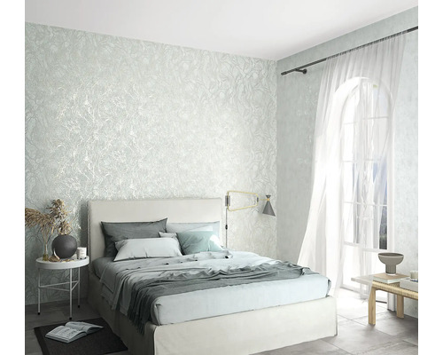 Schlafzimmer mit strukturierten Tapeten, Bett und Fenstern für eine helle Raumatmosphäre