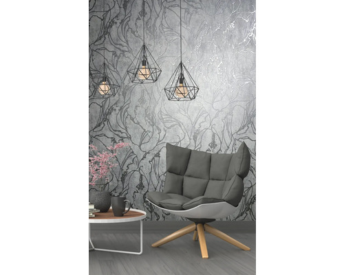 Wohnzimmer mit Sessel, Tisch und geometrischen Hängelampen vor einer floralen Tapete