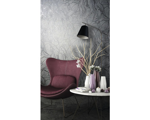 Wohnzimmer mit Sessel, Tisch und floral gemusterter Tapete