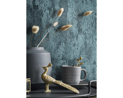 Dekoratives Stillleben mit Tapete, goldener Pfauenfigur, Tasse und Vase