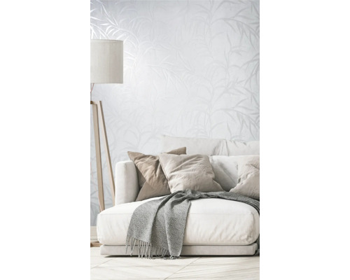 Wohnzimmer mit Couch, Kissen, Decke, Stehlampe und Tapete mit Pflanzenmuster