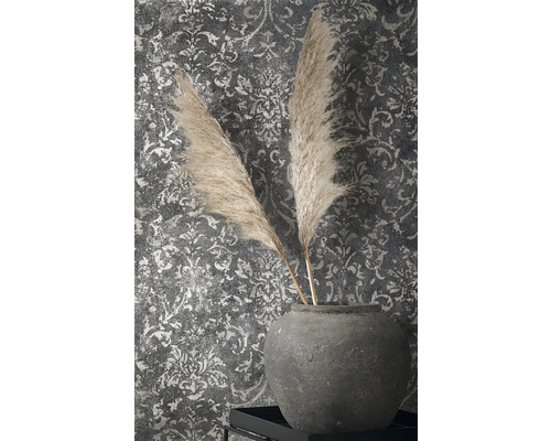Dekorative Federn in Steingutvase vor gemusterter Wandtapete