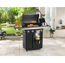 Grillszene im Freien mit Fleisch, Gemüse und Pommes Frites auf einem schwarzen Gasgrill mit vier Brennern.