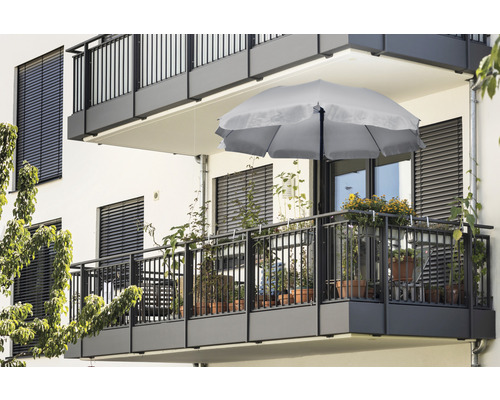 Balkon mit Sonnenschirm und verschiedenen Pflanzen in Töpfen.