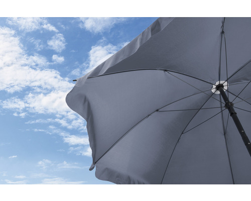 Geöffneter Sonnenschirm vor blauem Himmel mit Wolken