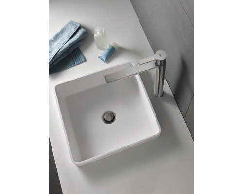 Auf einem Waschtisch befindet sich ein Aufsatzwaschbecken mit Armatur, Handtuch und Kosmetikartikeln