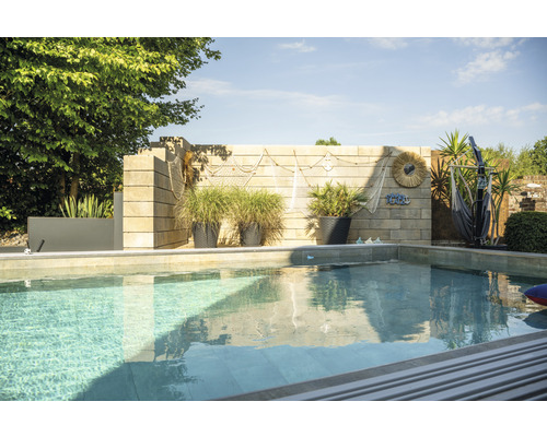 Schwimmbad mit Steinmauer, Pflanzgefäßen und maritimer Dekoration im Garten
