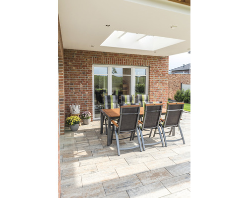 Gartensitzgruppe auf gepflasterter Terrasse mit Ziegelwand