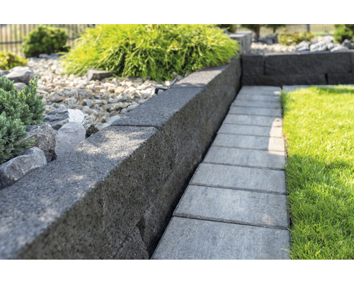 Gartenansicht mit Rasen, Mauersteinen und Gehwegplatten