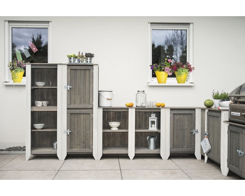 Gartenküche mit Holzschränken und Regalen auf einer Terrasse vor einem weißen Haus