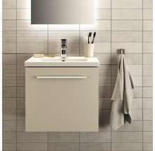Badezimmer-Szene mit Waschtischunterschrank, Waschbecken, Armatur, Spiegel, Handtuch und Badaccessoires vor einer gefliesten Wand