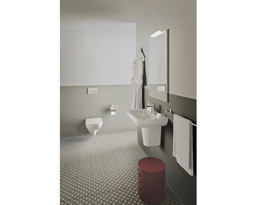 Helles Badezimmer mit Wand-WC, Waschbecken, Spiegel und gemusterten Fliesen