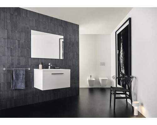 Modernes Badezimmer mit Waschbeckenunterschrank, Spiegel, Toilette und Bidet vor dunkler Wand