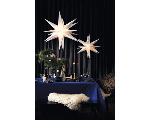 Festlich gedeckter Tisch mit Weihnachtsdekoration und beleuchteten Papiersternen