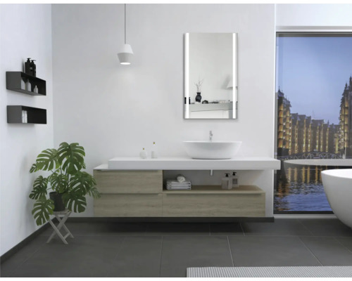 Modernes Badezimmer mit Waschtisch, Spiegel mit Beleuchtung, Badewanne und Pflanze