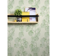 Wand mit Monstera-Tapete, Regal mit Pflanze, Zitrusfrucht, gelbem Notizblock und Bildern