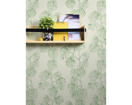 Wand mit Monstera-Tapete, Regal mit Pflanze, Zitrusfrucht, gelbem Notizblock und Bildern