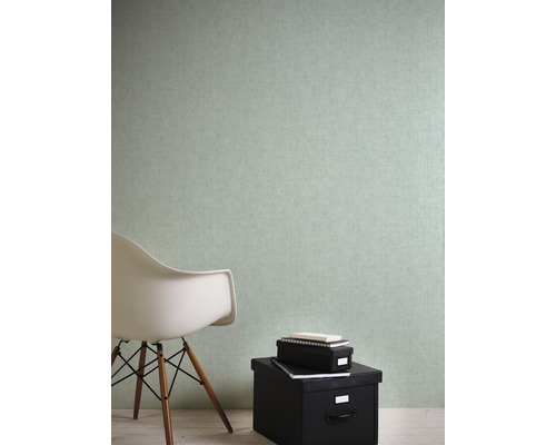 Wandgestaltung mit mintfarbener Tapete, kombiniert mit einem weißen Stuhl und schwarzen Aufbewahrungsboxen