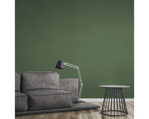 Wohnzimmer mit grauer Couch, Stehlampe und Beistelltisch vor grüner Wand