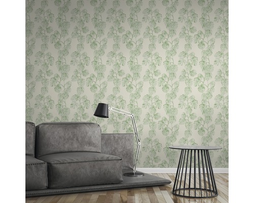 Wohnzimmer mit Tapete mit Monstera Pflanzenmuster, Sofa und Stehlampe.