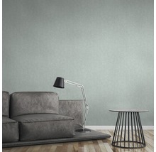 Wohnzimmer mit grauer Couch, Lampe und kleinem Tisch vor einer gemusterten Tapete