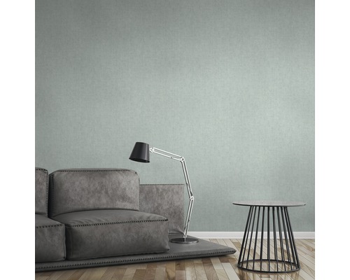 Wohnzimmer mit grauer Couch, Lampe und kleinem Tisch vor einer gemusterten Tapete