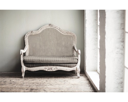Dekoratives Sofa im Vintage Stil vor einer Wand