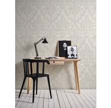 Ein Arbeitszimmer mit einem Schreibtisch, einem Stuhl, einer Lampe und einer Tapete mit floralem Muster.