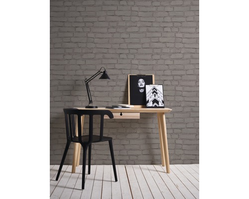 Einrichtungsszene mit Schreibtisch, Stuhl, Lampe und Backsteintapete