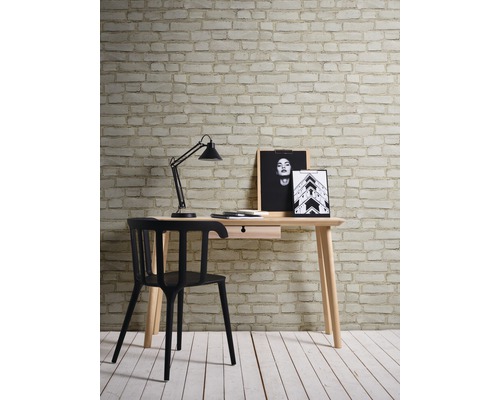 Arbeitszimmer mit Schreibtisch, Schreibtischlampe und Stuhl vor einer Wand mit Backsteintapete
