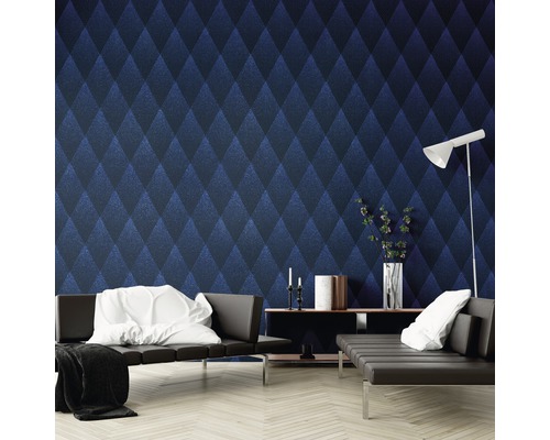 Ein Wohnzimmer mit einer Wand, die mit einer blauen Rautenmuster-Tapete dekoriert ist, darunter Sofas, ein Regal und eine Stehlampe.
