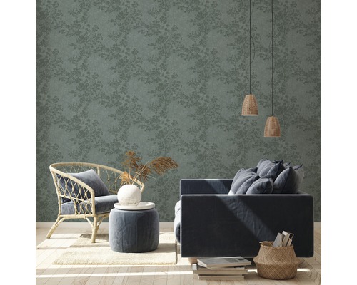 Wohnzimmer mit floral gemusterter Tapete, Sessel, Sofa und Beistelltisch.