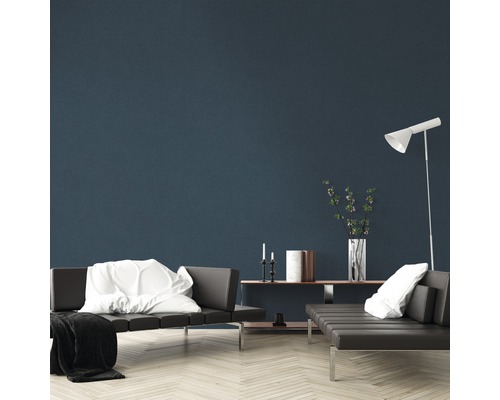 Wohnzimmer mit grauen Sofas, weißem Kissen, weißer Decke, Stehlampe und Dekorationsgegenständen auf einem Regal vor einer blauen Wand