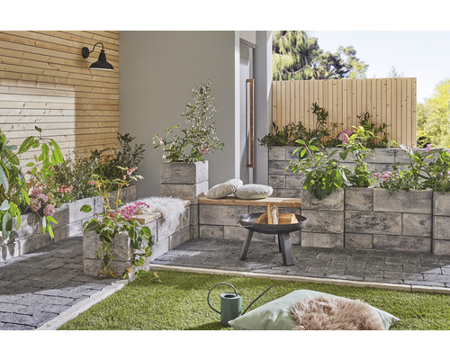 Gestalteter Außenbereich mit Pflastersteinen, Feuerstelle und Pflanzenkübeln