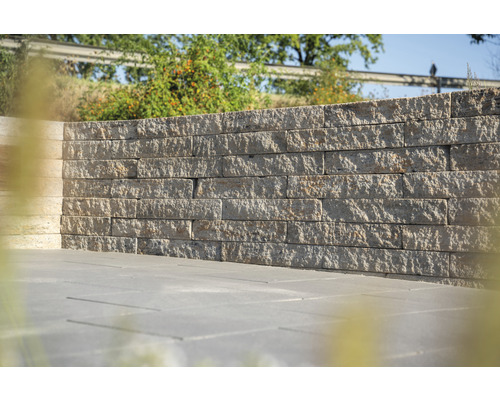 Gartenmauer aus Steinblöcken und Steinplatten auf dem Boden.