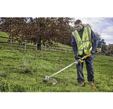 Eine Person trimmt Gras mit einem Akku-Rasentrimmer im Freien.